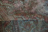 Folded vintage Malayer rug showing distressed pile, wear, and muted rust and blue tones.