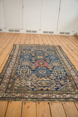 Vintage Malayer rug corner: navy field, madder red palmette, and antique ivory vine border.