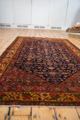 Intricate Herati motif on navy Malayer rug field and rich red floral border.