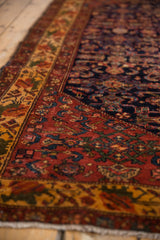 Vintage Malayer rug displaying deep blush floral border and navy blue Herati field.