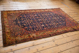 Vintage hand-knotted Malayer rug corner displays blush floral border and navy Herati field.