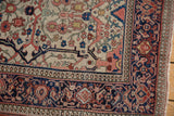 Antique Persian Farahan Sarouk rug corner, showing navy blue border and ivory field with intricate floral patterns.