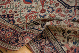 Textured fold of antique Farahan Sarouk rug, showing ivory field, madder red and navy floral motifs, and border.