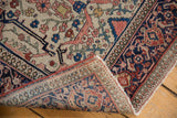 Antique Farahan Sarouk rug corner showing ivory floral field, navy border, and natural fringe.