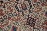 Antique Farahan Sarouk with ivory ground, curvilinear red, navy floral pattern, and visible wear.
