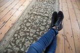 Distressed Hamadan runner's allover floral vine pattern in charcoal and faded ivory tones.