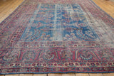 Worn indigo blue field with elongated vinery and intricate raspberry borders.