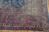 Vintage Yezd rug corner showing worn indigo field, foundation, and raspberry red floral borders.