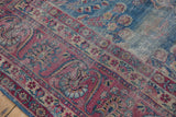 Yezd carpet detail: faded blue vinery field, raspberry floral border, visible foundation wear.