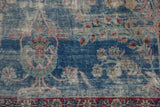 Worn indigo field of vintage Yezd carpet showing faded floral vinery and exposed foundation.