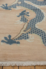 Dusty denim blue five-claw dragon motif on pale beige field of vintage Tibetan rug.