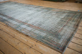 Angled view of a vintage Malayer runner showing its extensive wear and faded color palette.