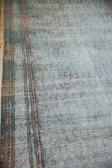Angled view of the distressed Persian Malayer showing wear across the knot heads and foundation.