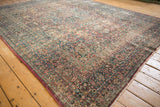 Distressed vintage Persian Meshed rug, corner detail highlighting intricate floral vinery and worn pile.