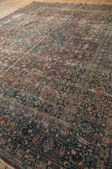 Distressed Meshed carpet showing intricate floral vinery, dusty teal, wine red, and beige worn pile.