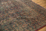 Detailed view of vintage distressed Persian Meshed rug with intricate vinery, faded hues, and visible foundation.