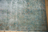Distressed Kerman carpet section with exposed foundation, blue, green, and sand floral motifs.