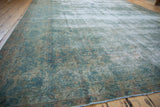 Distressed Kerman carpet detail, showing faded blue-green floral design and exposed foundation.