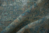 Folded vintage Kerman carpet with distressed blue-green floral pattern and exposed foundation.