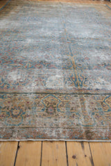 Angled close-up of distressed Kerman carpet, showing worn foundation, sky blue, gold, and red border motif.