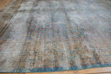 Distressed corner of Kerman carpet, showing exposed foundation and faded blue-gold tree of life.