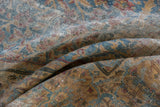 Distressed Kerman carpet with worn pile, visible foundation, faded blue, gold, and red hues.