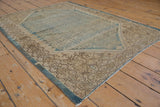 Distressed Malayer rug corner featuring worn pile, patterned brown border, and blue selvage.