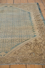 Vintage distressed Malayer rug's textured pile showing faded blue Herati pattern on ivory.