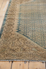 Distressed Malayer rug corner, featuring faded denim blue Herati motif and patterned antique ivory border.