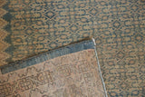 Distressed vintage Malayer rug corner, showing faded Herati motif pile and blue selvage.