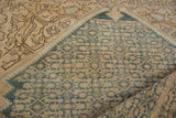 Folded vintage Malayer rug showing distressed dusty denim blue diamond motifs.