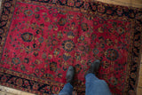 Fine Sarouk rug's raspberry field, displaying bursting floral motifs and navy border.
