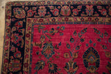 Fine hand-knotted Persian Sarouk rug corner, raspberry field, large navy border florals.
