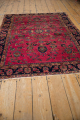 Vintage Sarouk rug border, with dark navy, raspberry, and beige floral patterns and fringe.