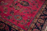 Intricate floral motifs on raspberry red field and dark navy border of a vintage Sarouk rug.