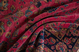 Vintage Sarouk rug's raspberry red field with intricate floral motifs and dark navy border.