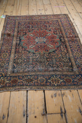 Corner of an antique Farahan Sarouk rug, showing worn pile, Herati motifs, and red floral border.