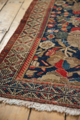 Hamadan rug corner: navy blue field with red pomegranate motifs, geometric borders, worn, fringe.