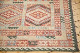Green wave motif border and fringe on a New Kilim carpet corner.