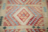 Brilliant geometric diamond and stepped patterns in red, blue, and beige on the New Kilim rug.