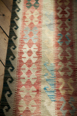Traditional geometric patterns in terracotta, muted blue, and ivory on the New Kilim carpet's edge.