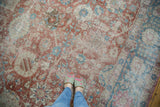 Distressed low-pile texture on a vintage Tabriz carpet with faded red and sky blue palmettes.