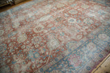 The decorative, distressed texture of a vintage Tabriz carpet in pale red and sky blue.
