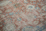 Faded vase and palmette motifs on the time-softened pile of a vintage Tabriz carpet.