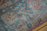 Angled view of a distressed Tabriz carpet's low pile with muted sky blue and dusty rose florals.