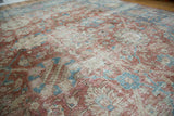Angled view of a vintage Tabriz rug's distressed texture in red, sky blue, and beige.