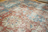 Distressed texture over palmette designs in celadon red and sky blue on a vintage Tabriz carpet.