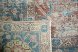Corner of a distressed Tabriz carpet folded over to show the hand-knotted weave and low pile.