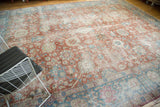 A distressed Tabriz rug showing time-softened red and sky blue tones in a styled setting.