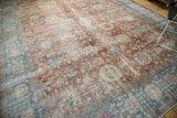 Angled view of a distressed Tabriz rug's faded celadon red field and sky blue border.